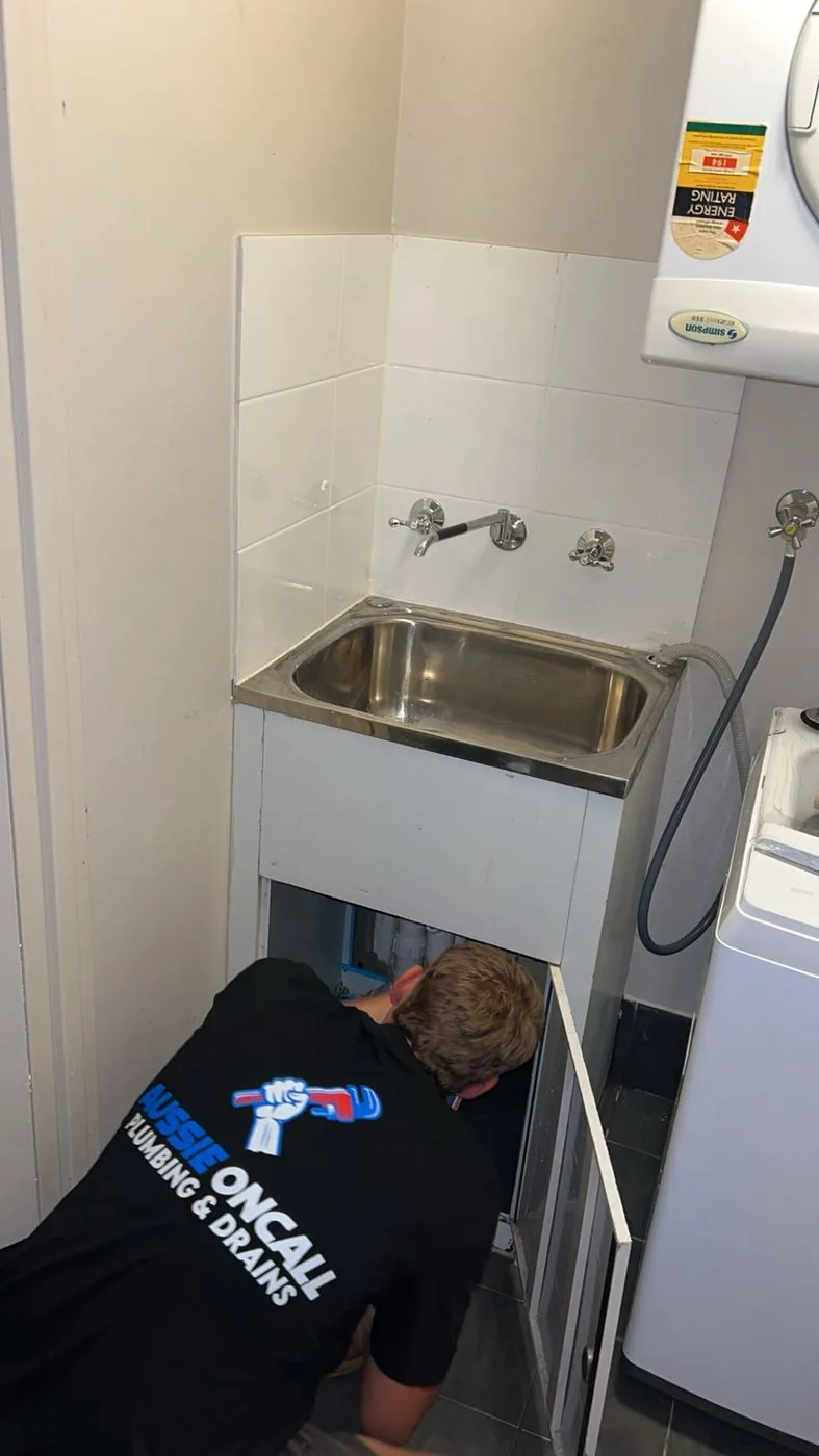 Plumber working on the laundry tub plumbing