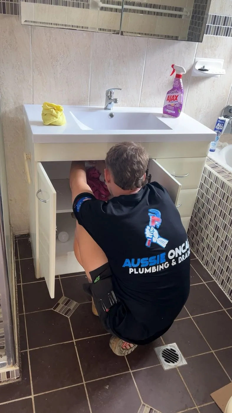 Plumber repairing the waste under a bathroom vanity