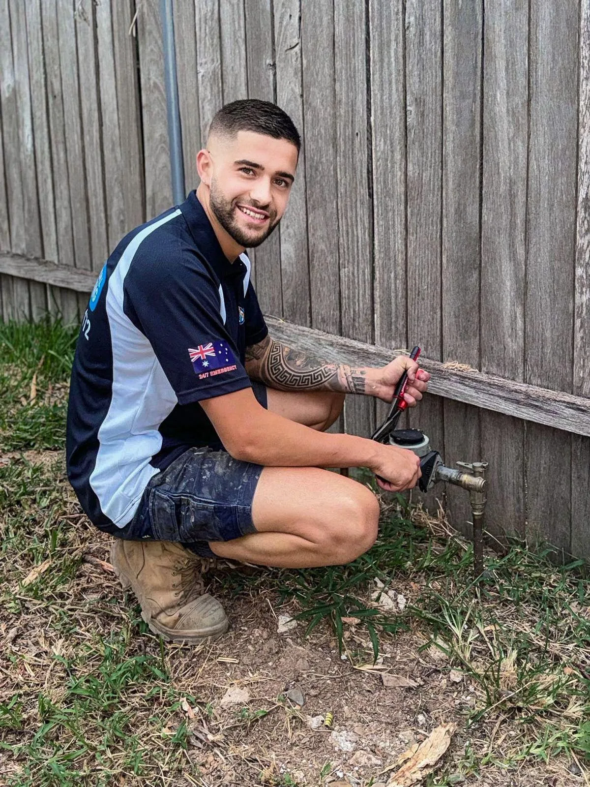 Plumber servicing an outdoor tap at a garden wall